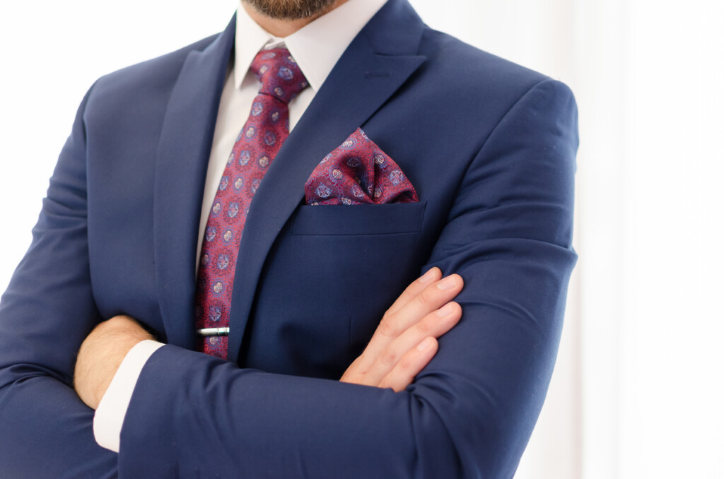 Suited businessman posing in front of camera with crossed hands.